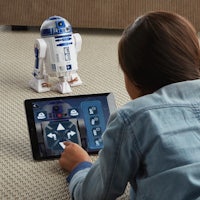 a girl is playing with a r2d2 toy on the floor